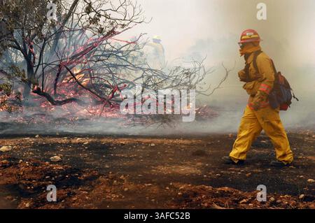26 octobre 2003 ; San Diego, CA, États-Unis ; les pompiers du Miramar Fire Dept. combattent un petit feu de broussailles sur le côté est d'un hangar à bord de la Marine corps Air Station (MCAS) Miramar, Calif. Le feu de broussailles fait partie des efforts continus pour combattre les feux de forêt qui font rage en Californie. Les autorités estiment que plus de 890 kilomètres carrés ont brûlé et que 17 personnes ont péri. Les multiples incendies ont brûlé plus de 300 000 acres de terre et cet événement catastrophique est considéré comme l'un des incendies les plus meurtriers de l'État depuis plus d'une décennie. (Image de crédit : ZUMA Press/ZUMAPRESS.com) Banque D'Images