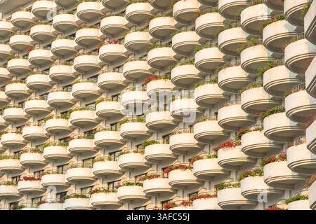 Motif répétitif de balcons arrondis sur la façade du bâtiment résidentiel avec des boîtes à fleurs et de la verdure, Bangkok, Thaïlande. Symétrie, géométrique Banque D'Images