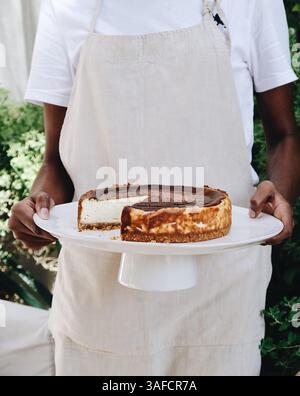 Personne tenant le cheesecake fait maison sur le stand à gâteaux Banque D'Images