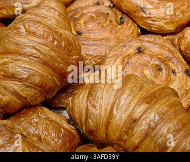 Différents types de pâtisseries traditionnelles à base de pâte feuilletée - croissants et petits pains aux raisins secs, gros plan, fond de boulangerie abstrait Banque D'Images