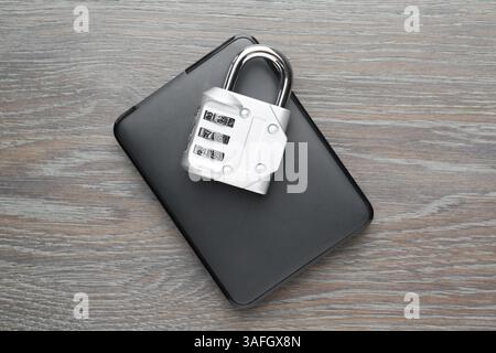 Disque dur et cadenas à combinaison sur table en bois gris, vue de dessus Banque D'Images