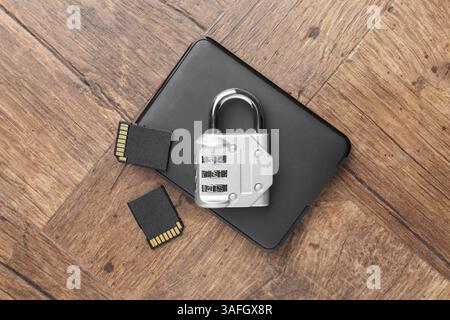 Disque dur externe, cartes mémoire SD et cadenas à combinaison sur table en bois, plat Banque D'Images
