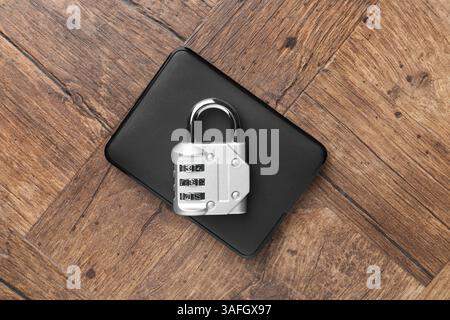 Disque dur externe et cadenas à combinaison sur table en bois, vue de dessus Banque D'Images