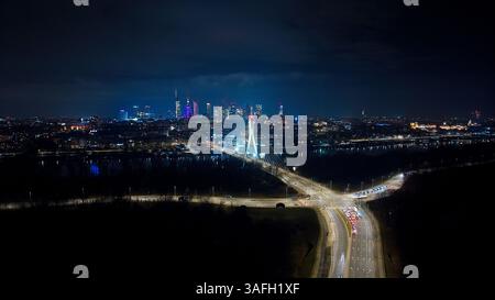 La magie urbaine de Varsovie : gratte-ciel, routes chatoyantes et reflets dorés de la ville qui brillent dans la nuit. Banque D'Images