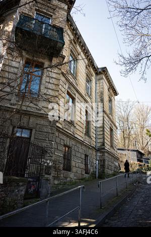 Lviv, Ukraine - 06 avril 2025 : un bâtiment historique en pierre avec des éléments architecturaux et une personne debout à proximité à Lviv, Ukraine. Banque D'Images