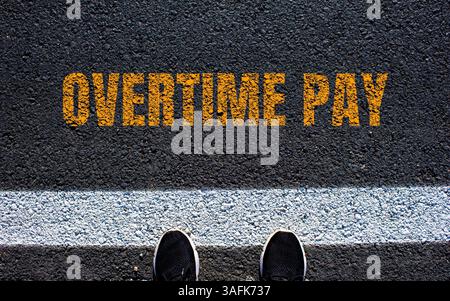 Message de rémunération des heures supplémentaires écrit sur une route asphaltée. Symbole conceptuel de rémunération des heures supplémentaires. Copier l'espace. Banque D'Images