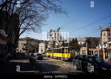 Lviv, Ukraine - 06 avril 2025 : tramway jaune dans une rue pavée entourée d'une architecture historique à la lumière du jour à Lviv, Ukraine. Banque D'Images