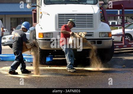 Photo prise lundi (14/02/05) : (2) des travailleurs de Diversified Environmental services, Inc de Tampa ont étalé un matériau absorbant sur le carburant diesel déversé sur N. Florida Ave. dans un effort pour nettoyer la route afin que la circulation aux heures de pointe puisse reprendre vers le nord. Fuite de carburant diesel du réservoir de carburant d'un camion semi-tracteur (image de crédit : St Petersburg Times/ZUMAPRESS.com) Banque D'Images