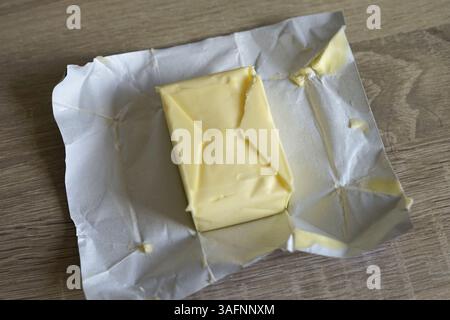 paquet ouvert de beurre jaune laitier sur une table en bois préparée pour la cuisson de friture de pâtisserie de petit déjeuner Banque D'Images