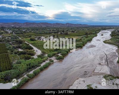 Vue aérienne de la rivière Fiambalá ou Saujil à Catamarca, Argentine. Capturée par drone, la rivière serpente à travers le village avec la majestueuse montagne des Andes Banque D'Images