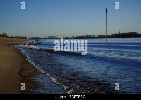 Les petites vagues rencontrent doucement une plage de sable calme sous un ciel clair, Weserstrand 26931 Oberhammelwarden-Allemagne Banque D'Images