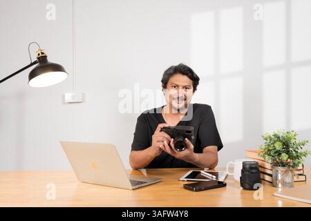 Homme asiatique senior nettoyant et vérifiant la caméra à la maison. Appareil photo et plusieurs lentilles de caméra sur la table basse. Bonne vie de retraite, passe-temps et intérêts fo Banque D'Images