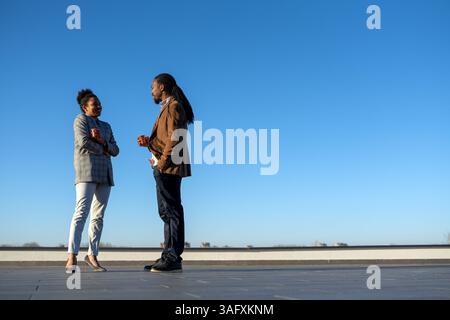 Un homme et une femme d'affaires joyeux habillé dans chic décontracté ayant une conversation sur le café en pause Banque D'Images