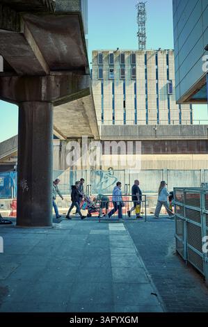 Les piétons passent une file unique devant un site de démolition fermé Banque D'Images