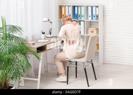 Femme mature souffrant de douleurs au cou au bureau Banque D'Images