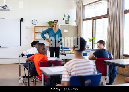 Enseignante indienne debout dans la classe, s'engageant avec les élèves pendant la leçon d'école Banque D'Images