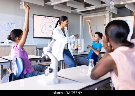 Engager les étudiants dans la classe de sciences, enseignante indienne utilisant le microscope et les béchers Banque D'Images