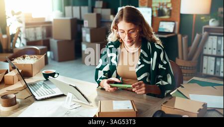 Code à barres, logistique et téléphone avec la boîte de balayage de femme dans le bureau pour la livraison ou le suivi d'expédition. App, photographie et chaîne d'approvisionnement avec personne dans Banque D'Images