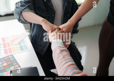 Travail d'équipe et collaboration. Un groupe de collègues célébrant le succès avec un coup de poing pour renforcer l'unité et la coopération. Banque D'Images