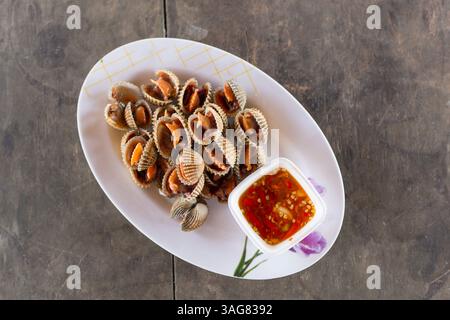 Cockles fruits de mer bouillis dans le plat sur la table en bois au restaurant Banque D'Images