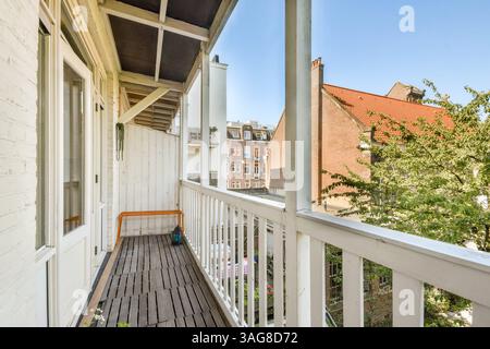 Un balcon confortable donne sur un paysage urbain animé, avec des planchers en bois et des balustrades, entouré de verdure et de bâtiments qui capturent l'essence de la vie urbaine. Banque D'Images
