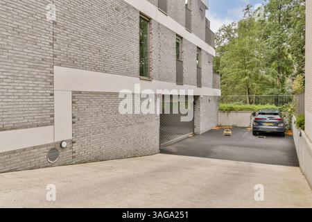 Une structure résidentielle contemporaine avec de grandes fenêtres et un garage bien entretenu, entouré de verdure. Banque D'Images