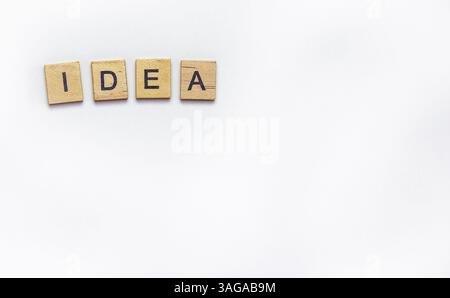 Les carreaux de lettres en bois épellent le mot 'IDÉE' sur un fond blanc, laissant amplement d'espace pour le texte ou la conception. Banque D'Images