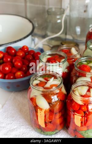 Conservation des tomates fraîches et du jus de tomate pour l'hiver, stocké dans des pots hermétiques pour une utilisation à long terme, table de cuisine avec des pots de tomates préparés Banque D'Images