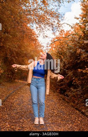Belle jeune femme riant et profitant d'une journée ensoleillée d'automne dans une ruelle. Banque D'Images
