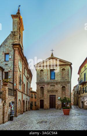 Aperçu de la Piazza Peretti avec l'église de San Giovanni Battista et le théâtre Orange avec les bâtiments en briques de terre cuite typiques de ce village. Banque D'Images
