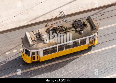 Le tramway jaune historique numéro 28 traverse une rue étroite de Lisbonne, Portugal. Symbole classique du charme de la ville, les transports en commun traditionnels Banque D'Images