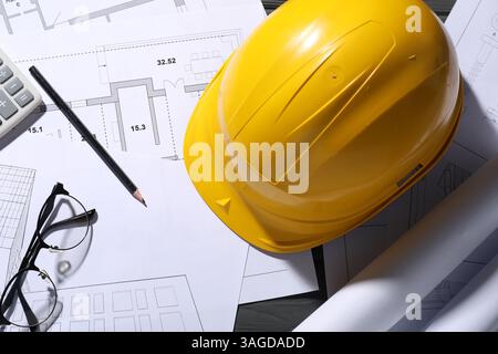 Différents dessins architecturaux, casque, crayon et verres sur table, pose à plat Banque D'Images