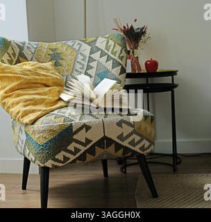 Fauteuil confortable et livre ouvert dessus, intérieur du salon. Banque D'Images