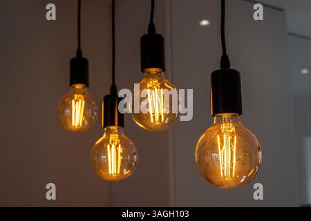 Une photo intérieure élégante de quatre ampoules à filament Edison lumineuses et chaudes suspendues au plafond. Banque D'Images