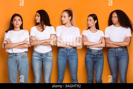 Les femmes multiraciales incontentées regardent la position féminine asiatique, fond jaune Banque D'Images