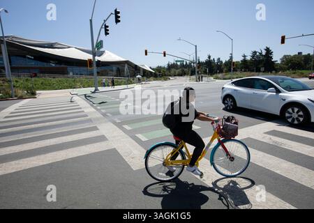 Mountain View, Californie, États-Unis - 30 août 2024 : une personne conduit un Google Bike devant le bâtiment du siège social de Google. Banque D'Images