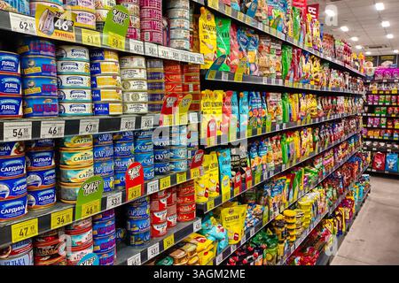 Ukraine, Romny, 27.03.2025 : une étagère de supermarché remplie de divers poissons en conserve, des collations emballées et des condiments, soigneusement agencés avec des étiquettes de prix et Banque D'Images