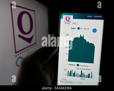Dans cette illustration photo, une personne tient un téléphone portable avec la page Web de la société mexicaine Qualitas Controladora S.A.B. de C.V. sur l'écran avec logo. Banque D'Images