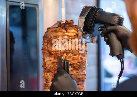 Turque CAG Kebab cuisine dans un barbecue. Cuire en tranchant la viande avec un couteau spécial Banque D'Images