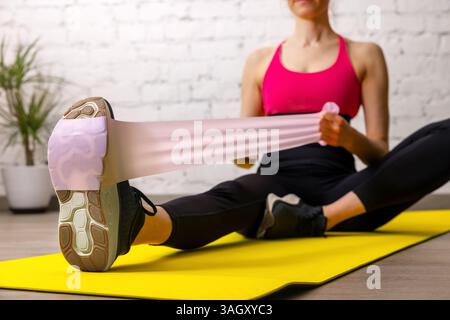 femme de fitness exerçant avec des bandes de résistance sur le tapis dans le gymnase. entraînement de force musculaire et d'étirement Banque D'Images