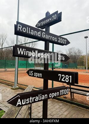 Kiev, Ukraine - 08 avril 2025 : panneau en bois sur le court de tennis indiquant les lieux célèbres des tournois et les distances respectives. Banque D'Images