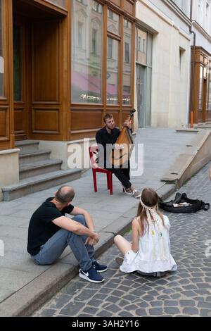 LVIV, UKRAINE - 20 juin 2021 : musicien de rue divertit couple amoureux de la performance sincère Banque D'Images