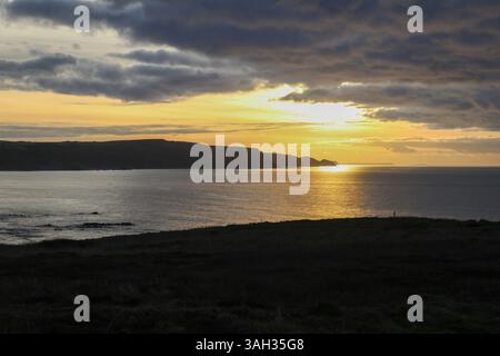 Coucher de soleil à l'heure d'or sur Widemouth Bay près de Bude, Cornouailles du Nord, Royaume-Uni, avec des falaises et une lumière côtière spectaculaire. Banque D'Images