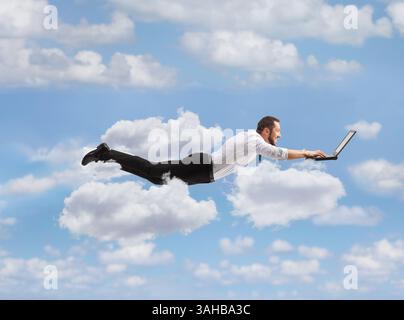 Homme volant et travaillant sur un ordinateur portable dans le ciel Banque D'Images