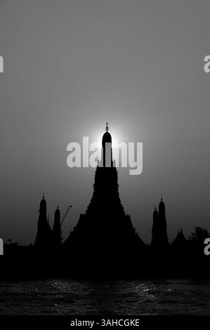 Le soleil se couche directement derrière la flèche centrale du Wat Arun en monochrome Banque D'Images