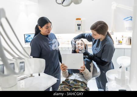 Dentiste féminine montrant des résultats de blanchiment des dents à un patient heureux tenant un miroir dans une clinique dentaire moderne Banque D'Images