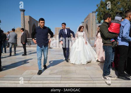 Une famille se préparant à poser pour des photos de mariage, des photos avec une mariée, un marié. Sur le site de la route de la soie, le Registan. À Samarcande, Ouzbékistan. Banque D'Images