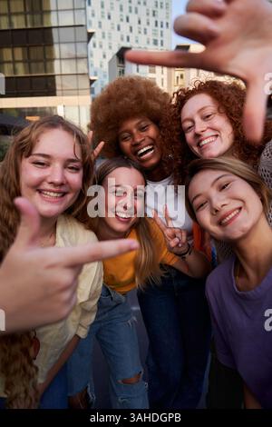 Selfie de femmes multiraciales amis faisant geste de cadre avec les doigts à l'extérieur dans la ville. Banque D'Images