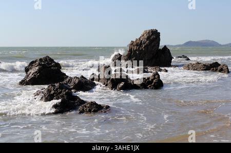 Vagues qui s'écrasent sur de grands rochers dans l'océan à une plage Banque D'Images