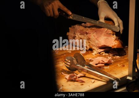 un homme a coupé un poulet rôti sur une planche à découper en bois prêt à servir pour la réception du dîner Banque D'Images